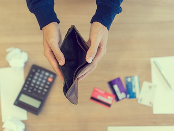 Man with empty wallet and bills to pay, representing the cost-of-living-crisis